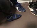 Male shoeplay in striped socks and different sneakers and watching a movie
