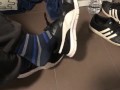 Male shoeplay in striped socks and different sneakers and watching a movie