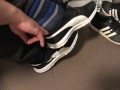 Male shoeplay in striped socks and different sneakers and watching a movie