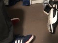 Male shoeplay in striped socks and different sneakers and watching a movie