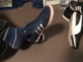 Male shoeplay in striped socks and different sneakers and watching a movie