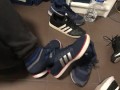 Male shoeplay in striped socks and different sneakers and watching a movie