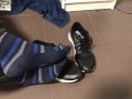 Male shoeplay in striped socks and different sneakers and watching a movie