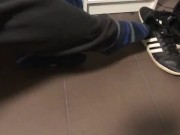 Male shoeplay in striped socks and different sneakers and watching a movie
