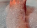 Hot blonde massaging her wet soapy feet in the bath