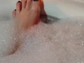 Hot blonde massaging her wet soapy feet in the bath