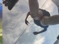 Tall girl in shorts jumping barefooted on a trampoline (slowed down) bottom view