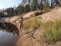 Naked girl walks along the river and forest
