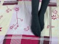 Girl in gray long socks on her legs caresses herself in bed