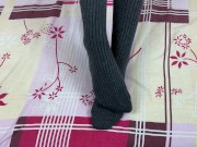Girl in gray long socks on her legs caresses herself in bed