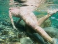 Голая девушка ныряет в океане и показывает свою киску