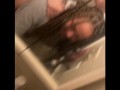 Blasian bent over bathroom sink while roommates in other room