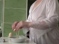 Mature MILF housewife with big natural tits is in the kitchen cooking scrambled eggs.