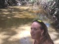 Cute long hair girl on her knees looking for shells to collect in popular spring creek