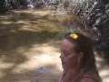 Cute long hair girl on her knees looking for shells to collect in popular spring creek