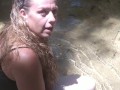 Cute long hair girl on her knees looking for shells to collect in popular spring creek