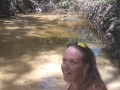 Cute long hair girl on her knees looking for shells to collect in popular spring creek