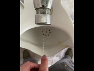 A man peeing in a public toilet, POV