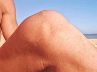 Sexy guy shows off his hard cock on a public beach with people walking by - girl gives him a handjob