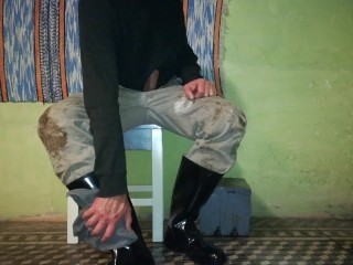 Farm man takes care of his rubber boots at the end of the day