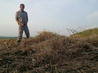 The farmer in rubber boots pees on the straw pile