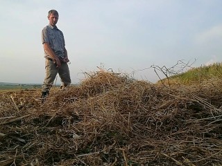 The farmer in rubber boots pees on the straw pile