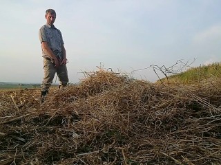 The farmer in rubber boots pees on the straw pile