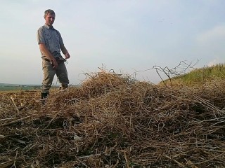 The farmer in rubber boots pees on the straw pile