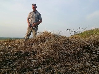 The farmer in rubber boots pees on the straw pile