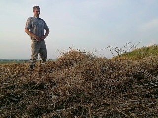 The farmer in rubber boots pees on the straw pile