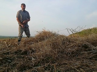 The farmer in rubber boots pees on the straw pile