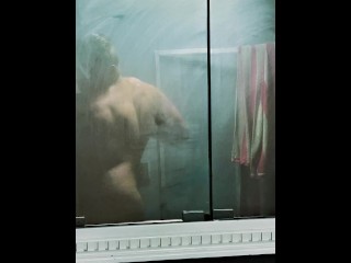 bodybuilder on a bulk flex in foggy mirror before shower