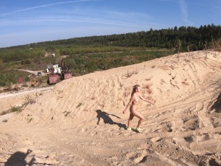 Nude girl walks in a sand quarry