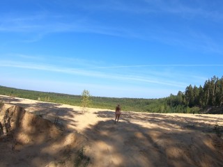 Nude girl walks in a sand quarry