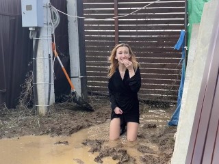 A fashionista in high-heeled boots climbed into a huge dirty pit with mud and water