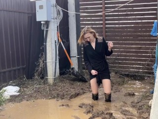 A fashionista in high-heeled boots climbed into a huge dirty pit with mud and water