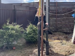 A fashionista in high-heeled boots climbed into a huge dirty pit with mud and water