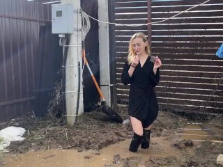 A fashionista in high-heeled boots climbed into a huge dirty pit with mud and water