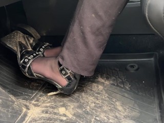 A girl in high-heeled shoes likes to listen to the sound of the engine and press the pedals with her