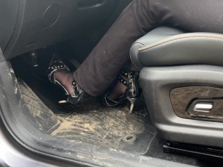 A girl in high-heeled shoes likes to listen to the sound of the engine and press the pedals with her