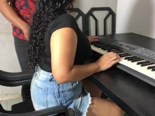 Una joven con curvas y una falda ajustada tomando su primera lección de teclado