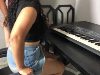 Una joven con curvas y una falda ajustada tomando su primera lección de teclado