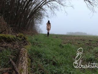 Naked stroll in a field by the forest on a foggy winter day