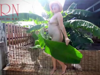 Rural striptease. Country girl dancing in the yard of her house Rustic striptease with banana leaf
