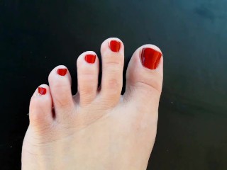 Red nail polish on toes. lady paints her toenails with red polish Regina Noir.