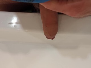 The boy is pissing into the washstand.