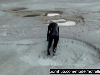 Super Hot Blond Girl In Black Latex Catsuit + High Heels And Sunglasses Bathes In The Mud - Mud Bath