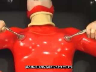 Sexy girl encased in red rubber catsuit loves medical games with mouth spreader and nipple clamps