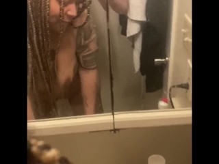 Blasian bent over bathroom sink while roommates in other room