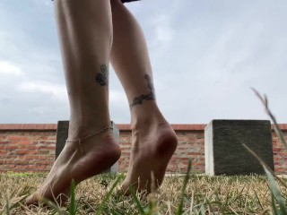 Slow motion milf barefoot in grass, wrinkled soles and red toes